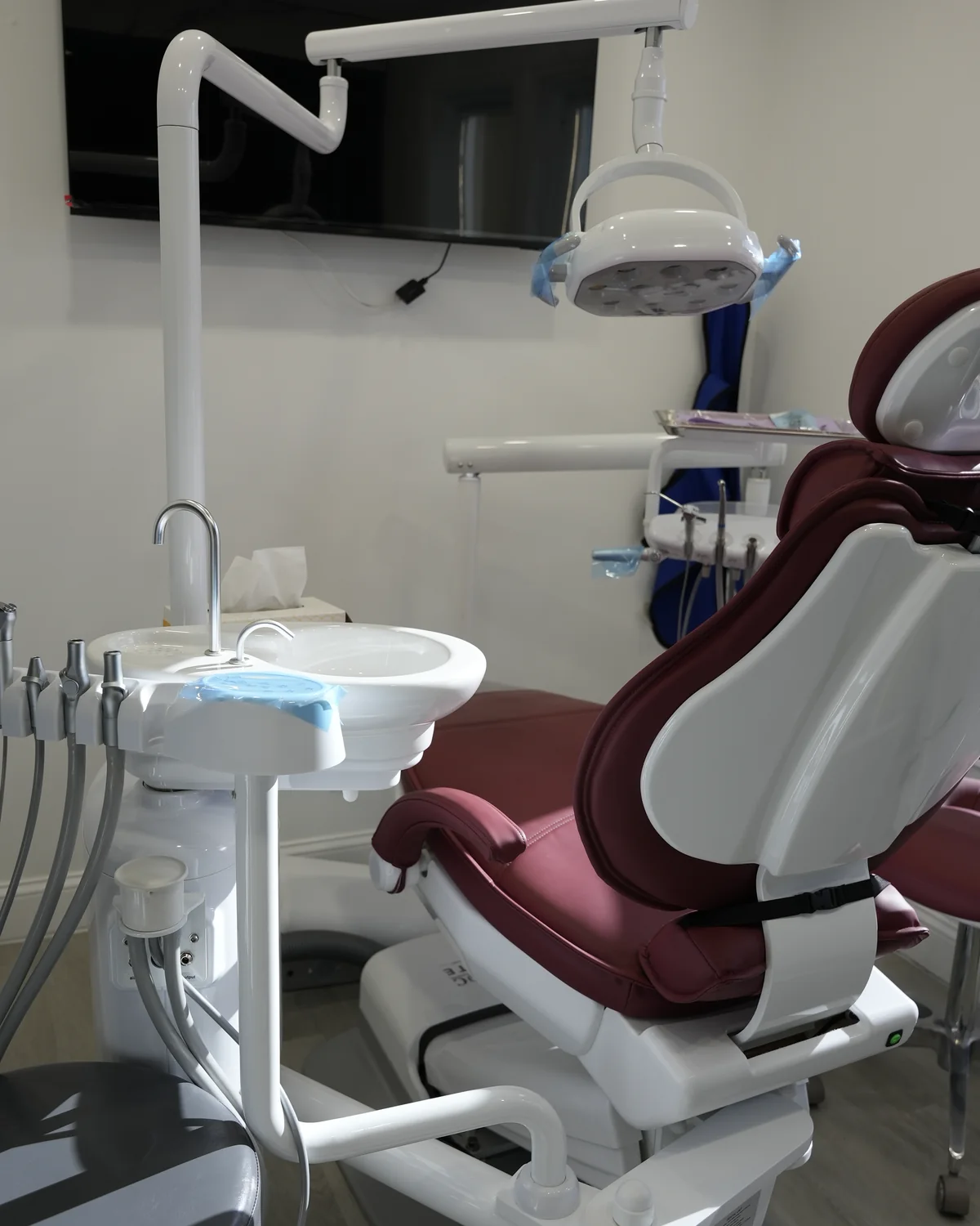 Treatment room at the Freeport office with a burgundy dental chair, overhead light and wall screen