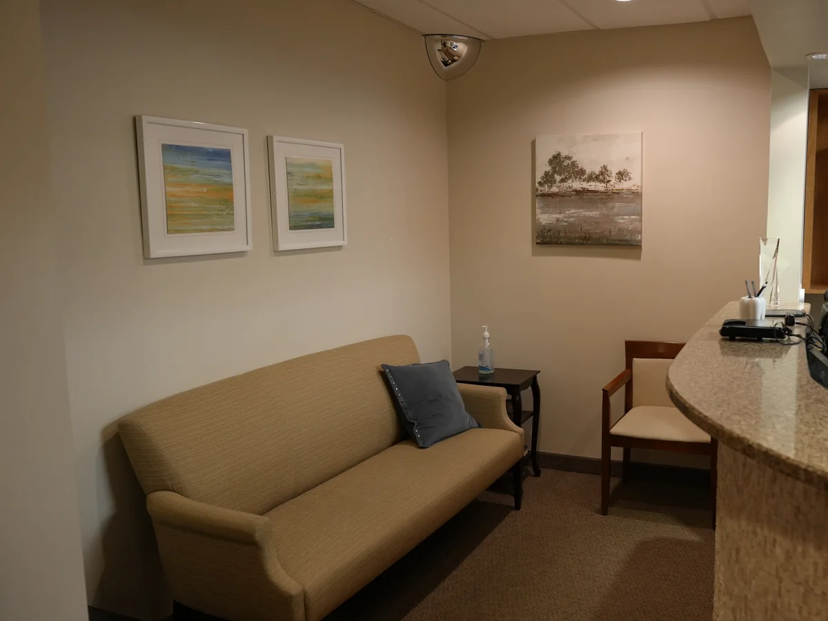 Waiting area with a sofa, an armchair and framed landscape prints at the Roslyn office